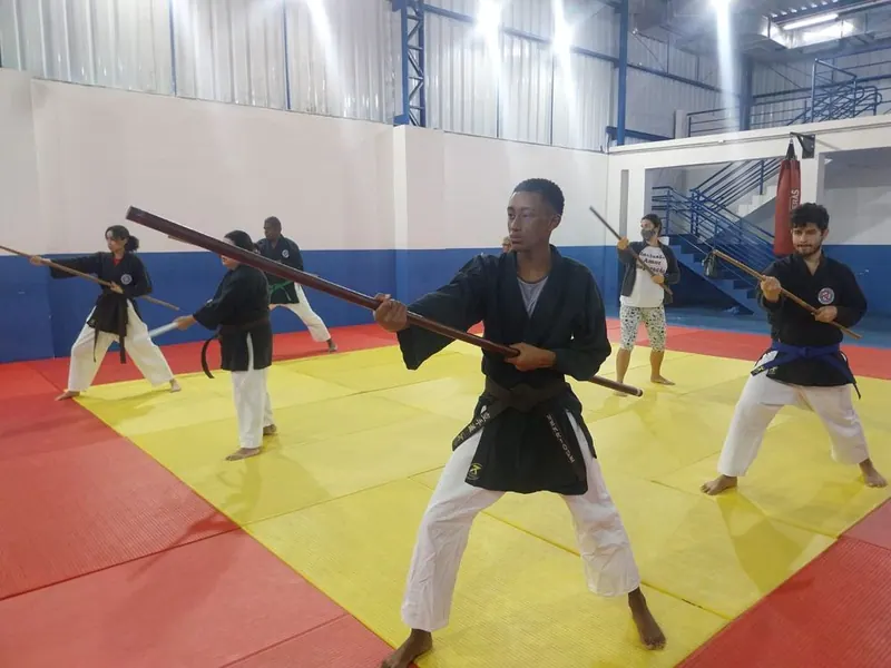 Treino de kobudo com bastões no tatame vermelho e amarelo