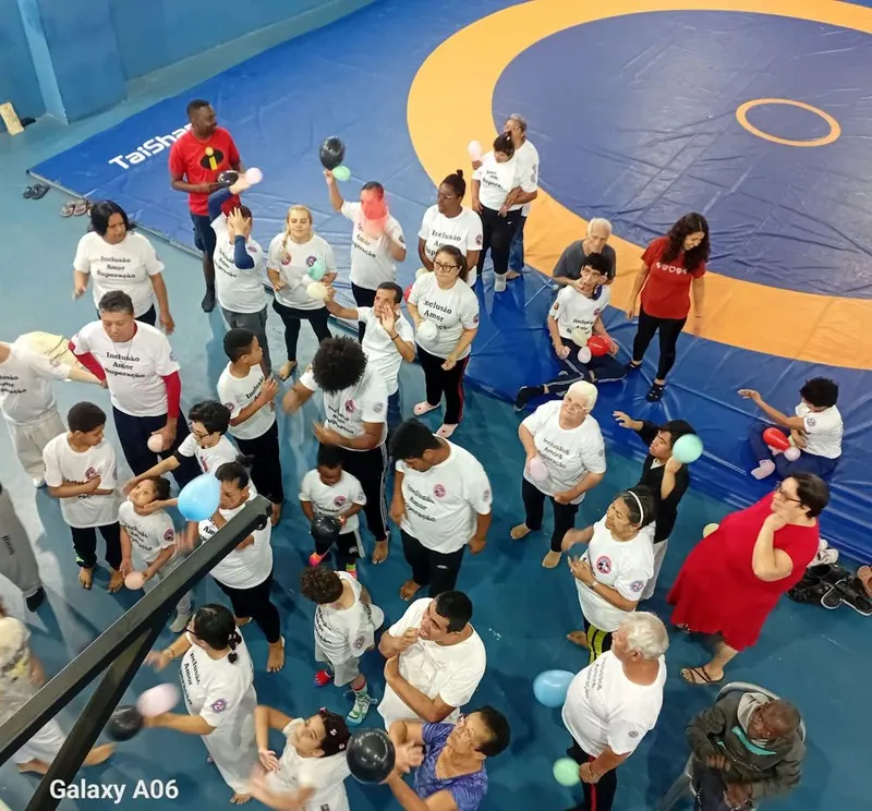 Grupo visto de cima sobre o tatame azul do ginásio, com balões